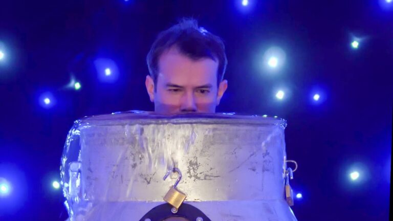 A person is submerged in a large block of ice with starry lights in the background.