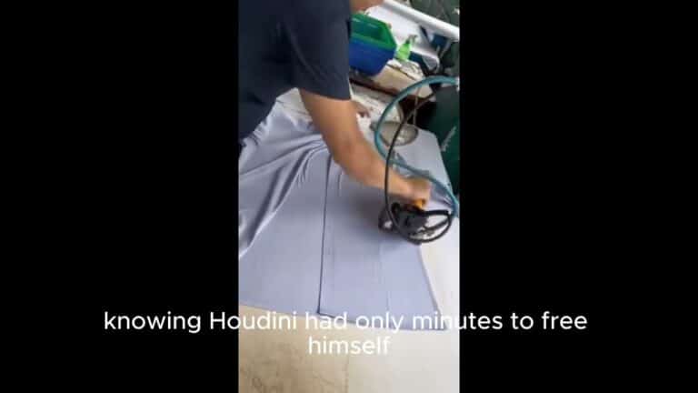 Person cutting fabric with a handheld electric cutter on a table.