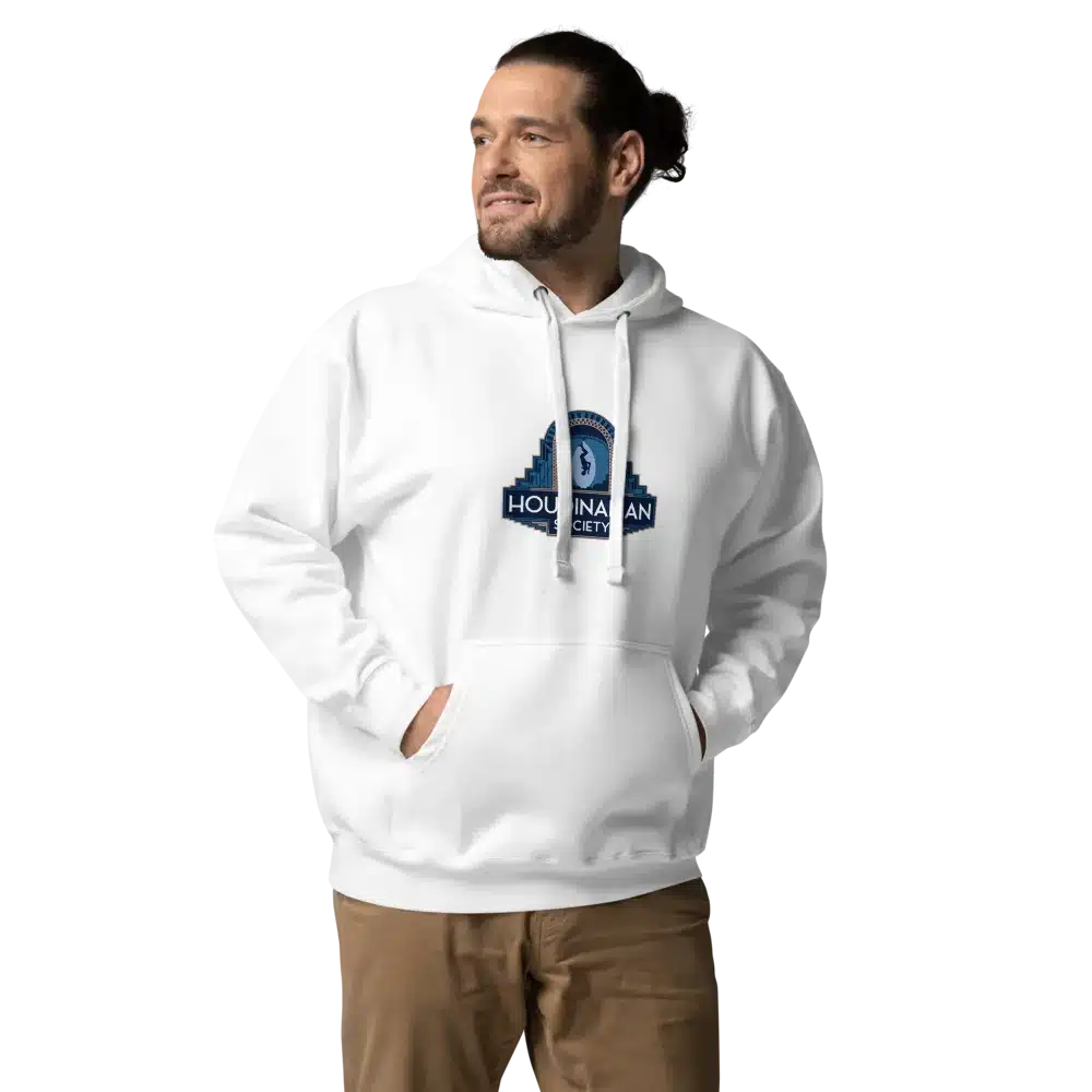 A person wearing a white hoodie with a logo on the chest, standing with hands in pockets, looking to the side.