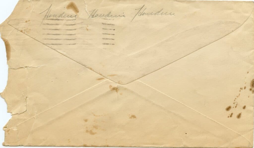 A worn, stained envelope with illegible handwritten text on the flap. The top left corner is damaged, and it shows signs of age and wear.