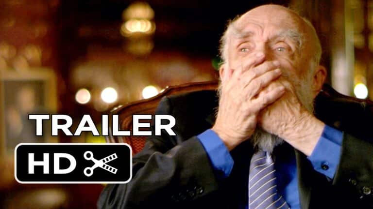 An elderly man with a beard and suit covers his mouth with his hands, appearing emotional. The image has a "trailer HD" label in the corner.