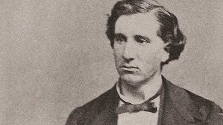 A vintage photograph of a man with wavy hair, wearing a bow tie and a jacket, looking to the side.