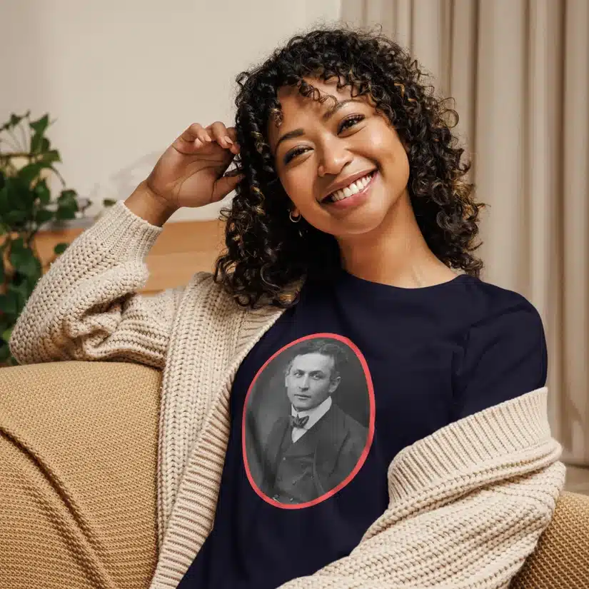 Smiling person with curly hair wearing a t-shirt featuring a historical portrait design, seated on a couch.