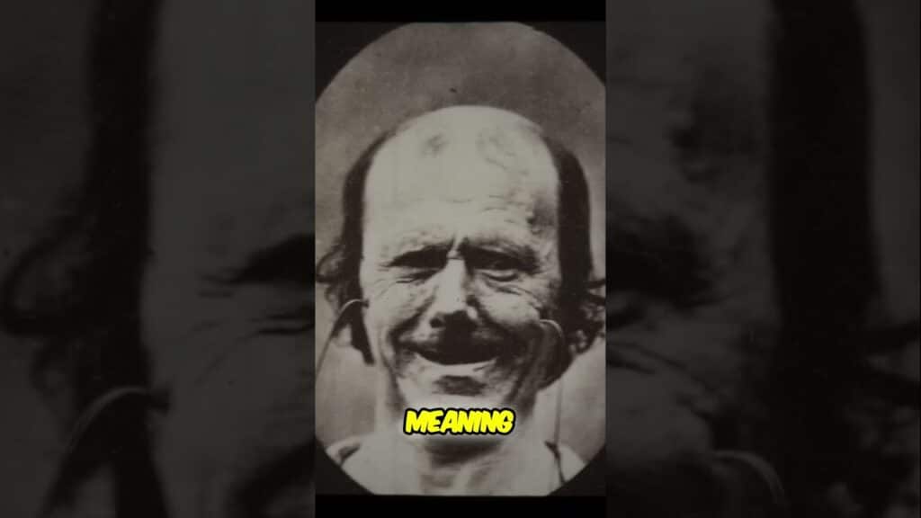 A black and white photo of a man with a pronounced smile and thinning hair. The word "MEANING" is overlaid at the bottom center.